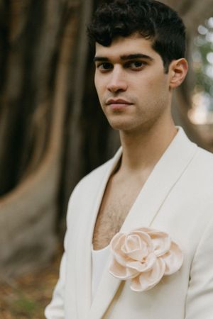 Close-up of white suit jacket with delicate blush rose boutonniere.