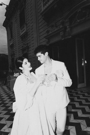 A vintage black and white photograph of a couple in white attire on a geometric floor.