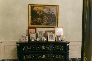 Vintage dresser displaying framed photographs and artwork in a classical interior.