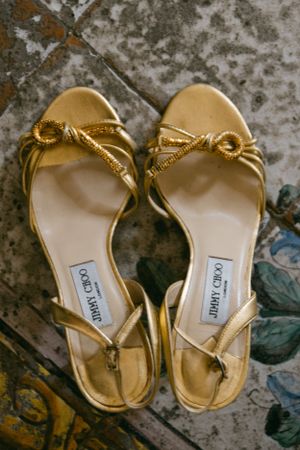 Pair of metallic gold Jimmy Choo sandals with knotted straps.