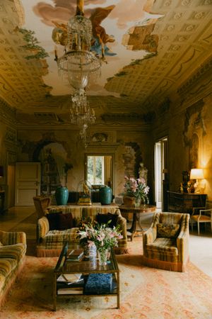 Elegant vintage living room with ornate chandelier and antique furniture in warm lighting.