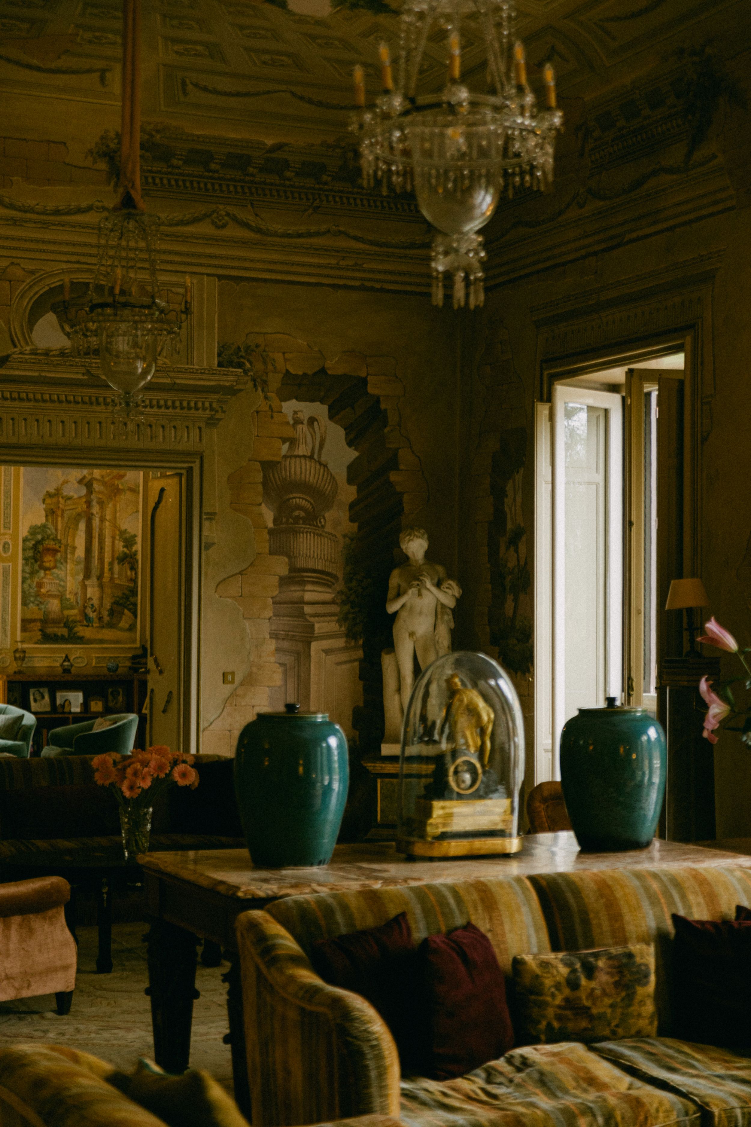Opulent room interior with large turquoise vases and crystal chandelier casting warm light.