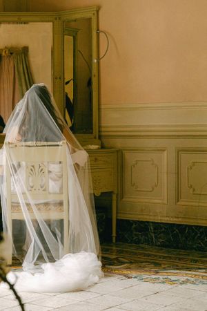 A flowing white wedding veil draped over a chair in an elegant vintage room.
