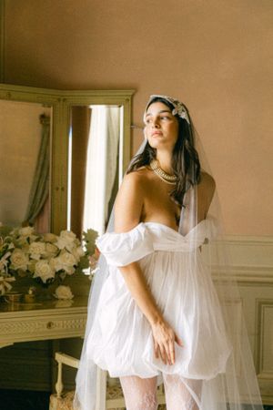A dreamy boudoir scene with white dress and veil in a classic room with ornate furniture.