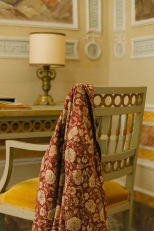Vintage chair with floral fabric draped over it next to an antique table lamp.