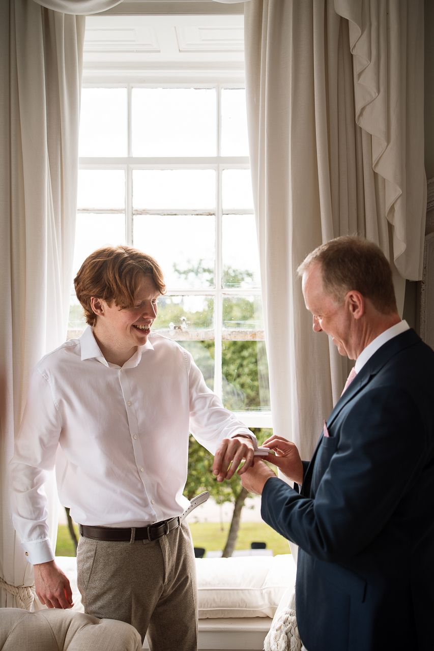 Getting ready scene by window with formal attire preparations.