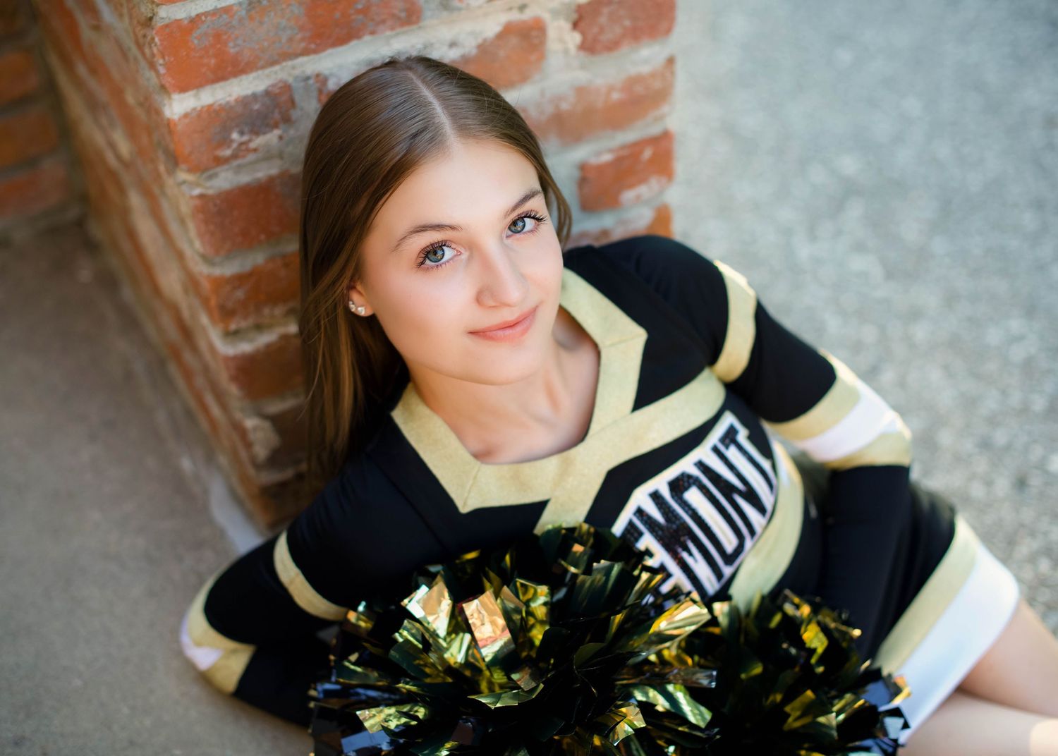 high school cheerleader smiling with her pompoms