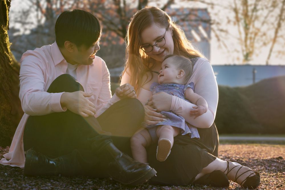 Family sitting together outdoors during golden hour in a park setting.