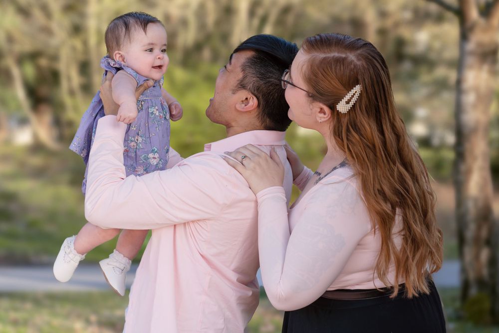 Family embracing and laughing together in a park during sunset.