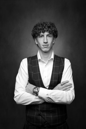 Black and white portrait of man wearing plaid vest and white dress shirt.