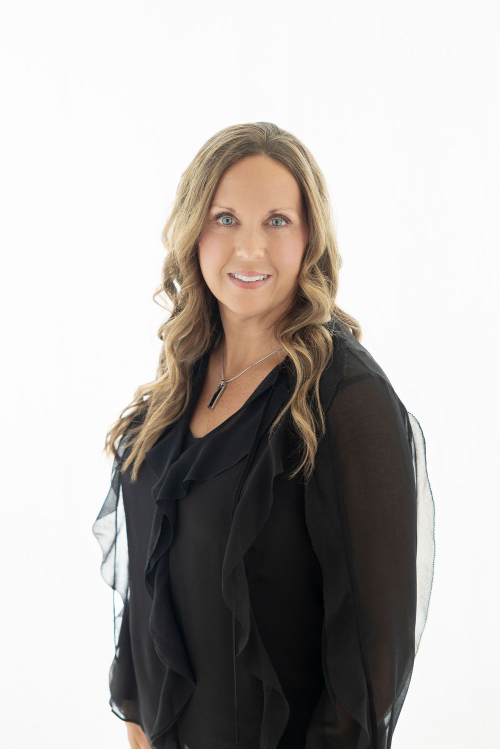 Professional woman in black blouse poses against white background.