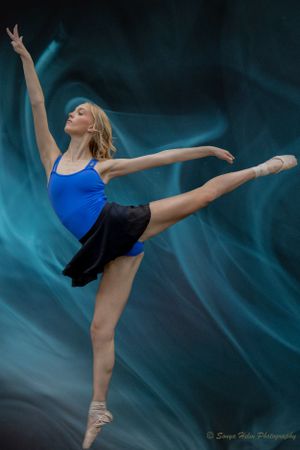Graceful ballet dancer in blue leotard performing arabesque against turquoise background. Sonya Helm Equine Photography, Bristol, TN