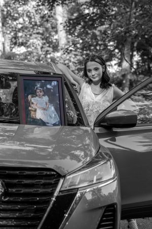 Black and white photo showing car door open with framed vintage photograph.