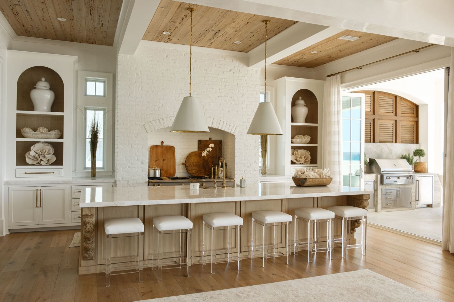 Modern open concept kitchen with white cabinets, wood beams, and pendant lighting.