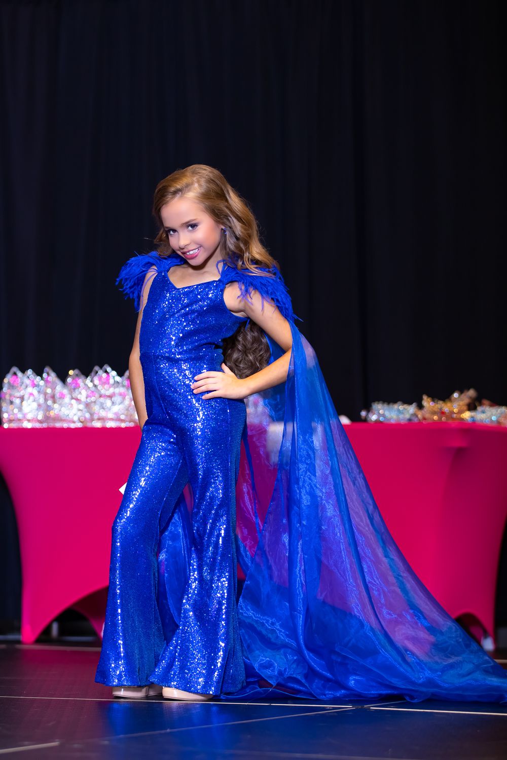 Stage performance features dramatic blue sequined costume with flowing cape details.