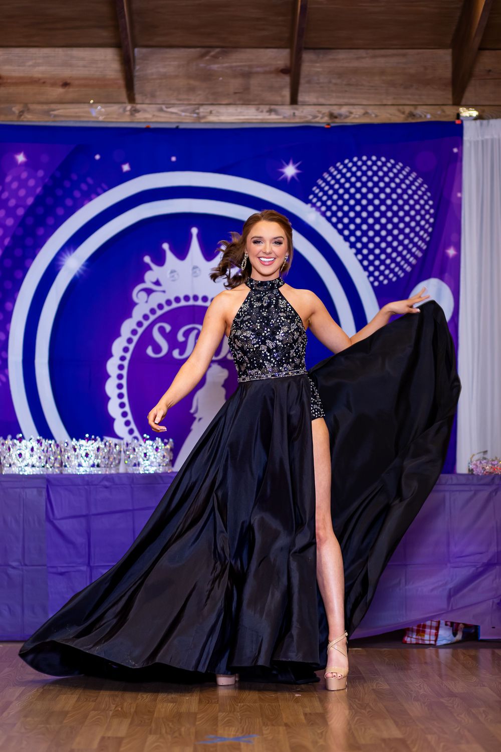 Navy high-neck evening gown with dramatic side slit and flowing train on stage.
