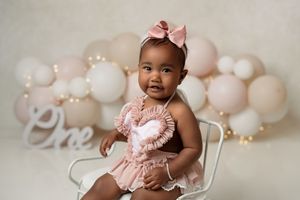 Baby girl enjoying her birthday cake during a professional studio cake smash session