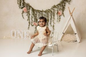 Cake smash photography of a baby enjoying a first birthday celebration in the studio