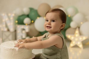 Baby playing with frosting during a fun and colorful cake smash photoshoot