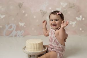 Baby playing with frosting during a fun and colorful cake smash photoshoot