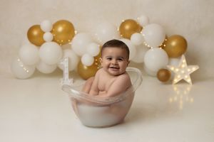 first birthday baby in a milk bath in a styled studio cake smash setup
