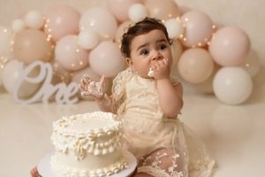 Baby enjoying a colorful cake smash photography session with a balloon garland backdrop
