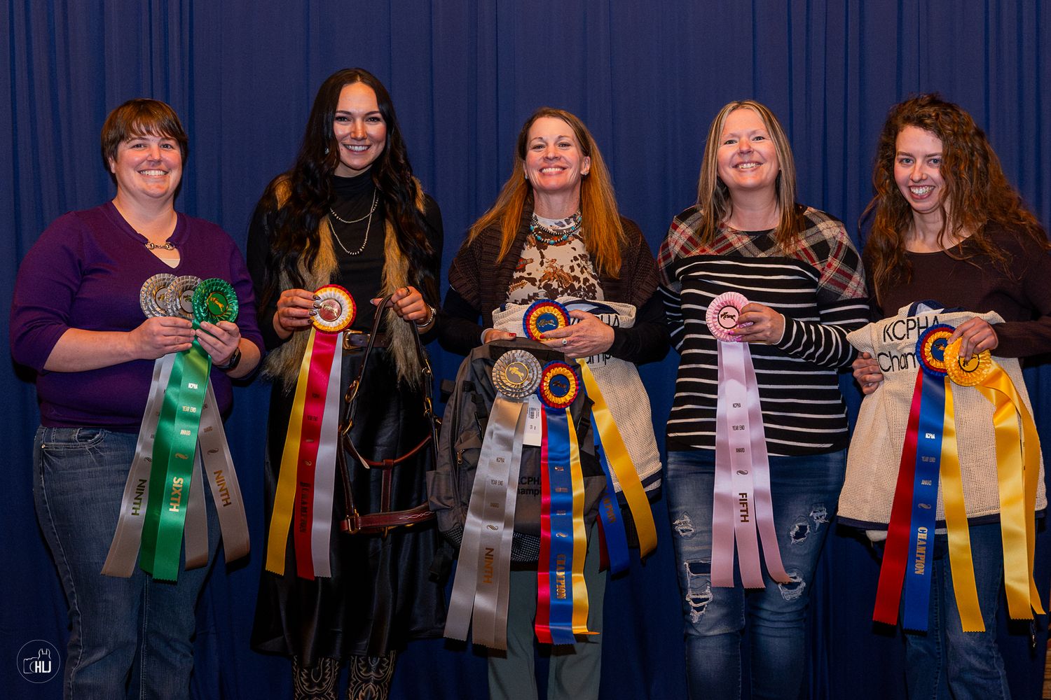 Prize winners pose together displaying colorful award ribbons from a contest or competition.