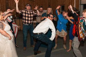 People dancing energetically at a wedding reception with guests in casual and formal attire enjoying the celebration.