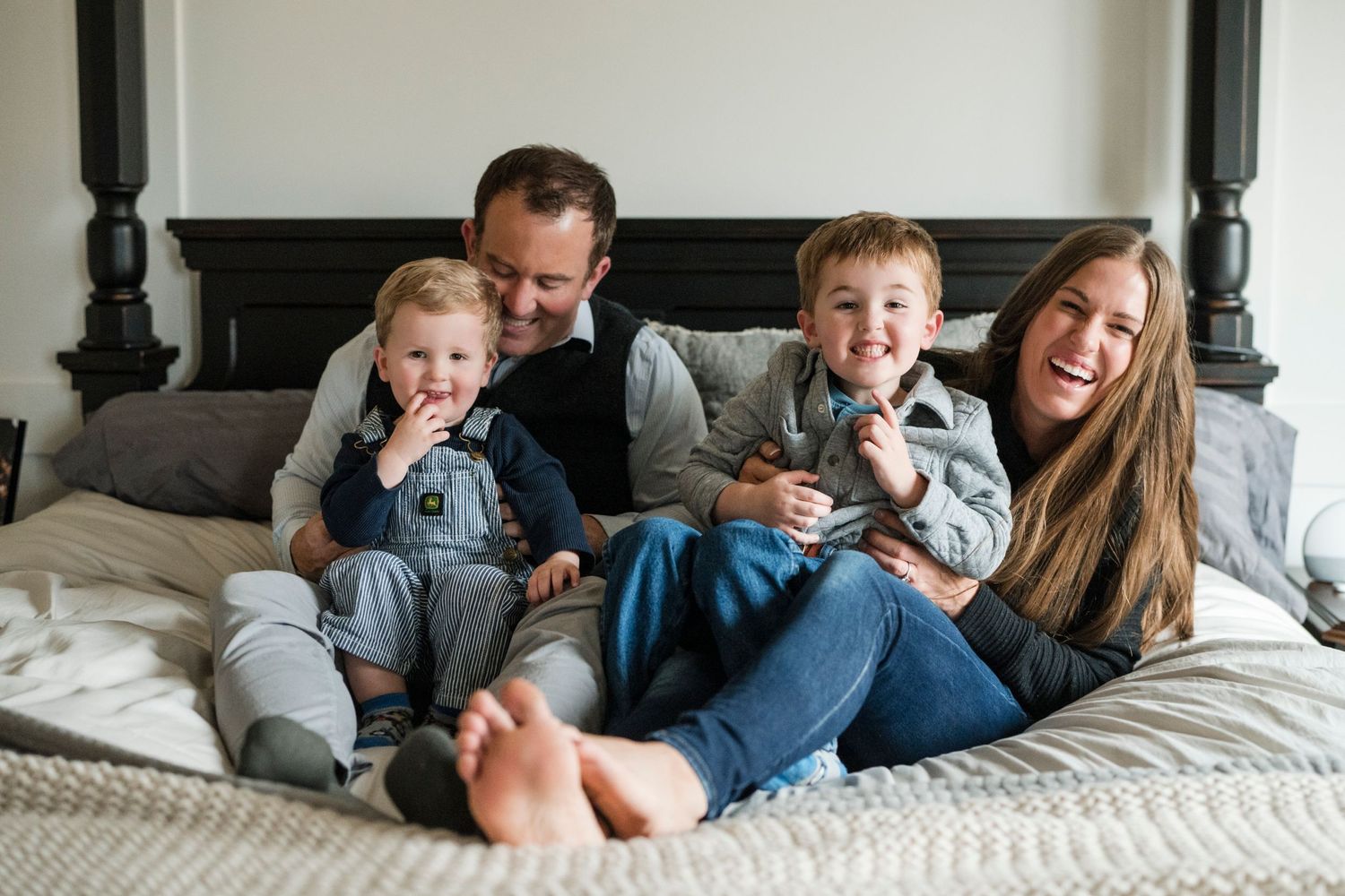 Family sharing laughs and cuddles on a cozy bed together.