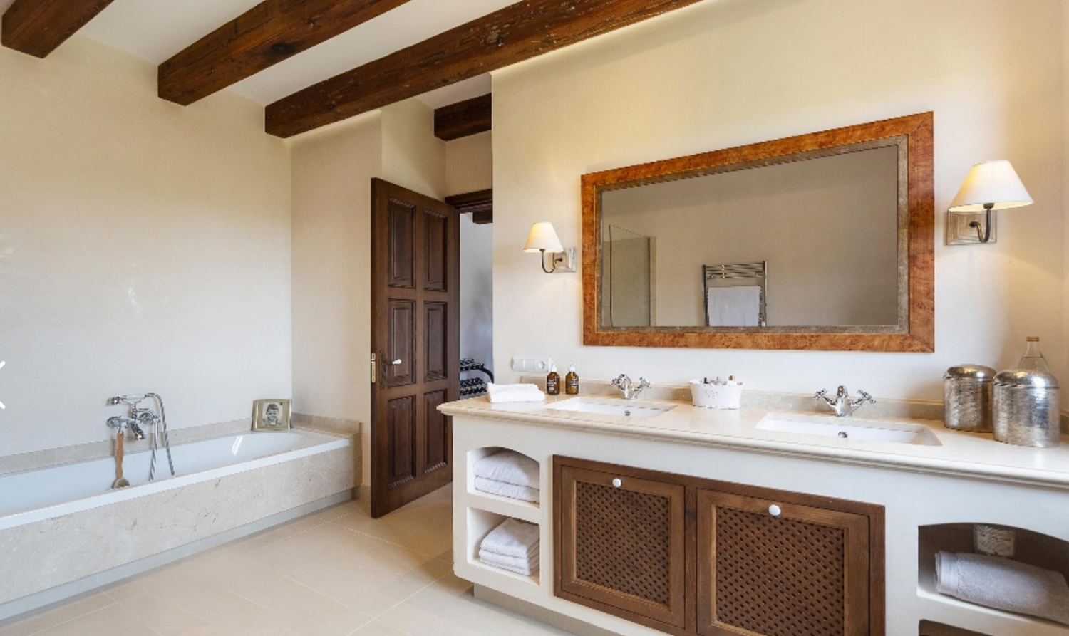 Spacious bathroom with exposed wooden beams, double vanity, and freestanding bathtub.