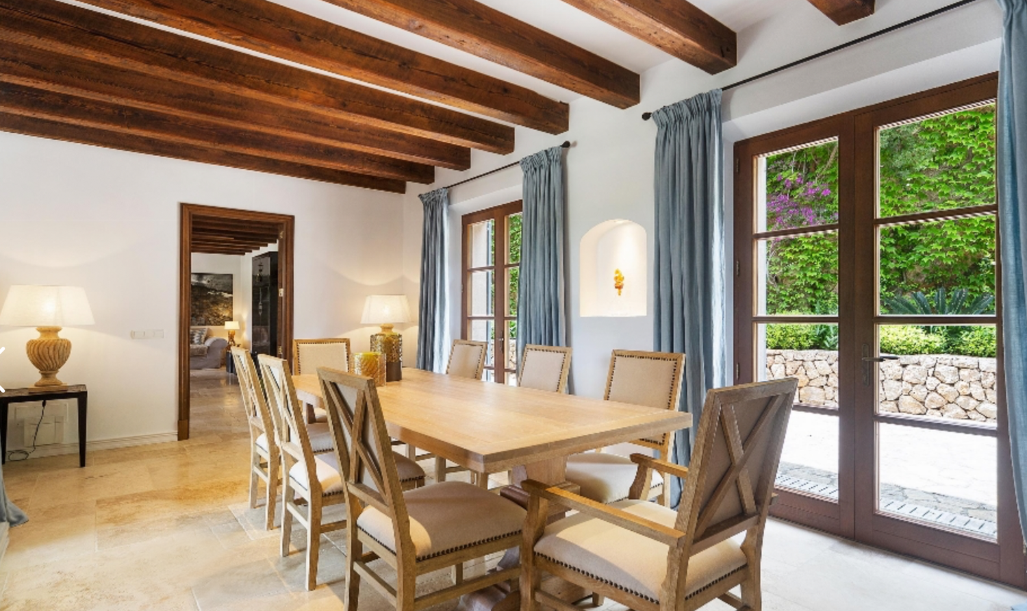 Dining room with wooden beam ceiling, stone floors, and French doors leading to outdoor space.
