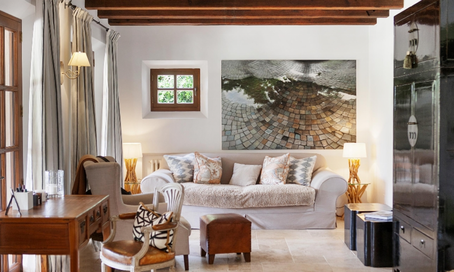 Cozy living room with white sofa, wooden beams, and large black and white coastal photograph on wall.