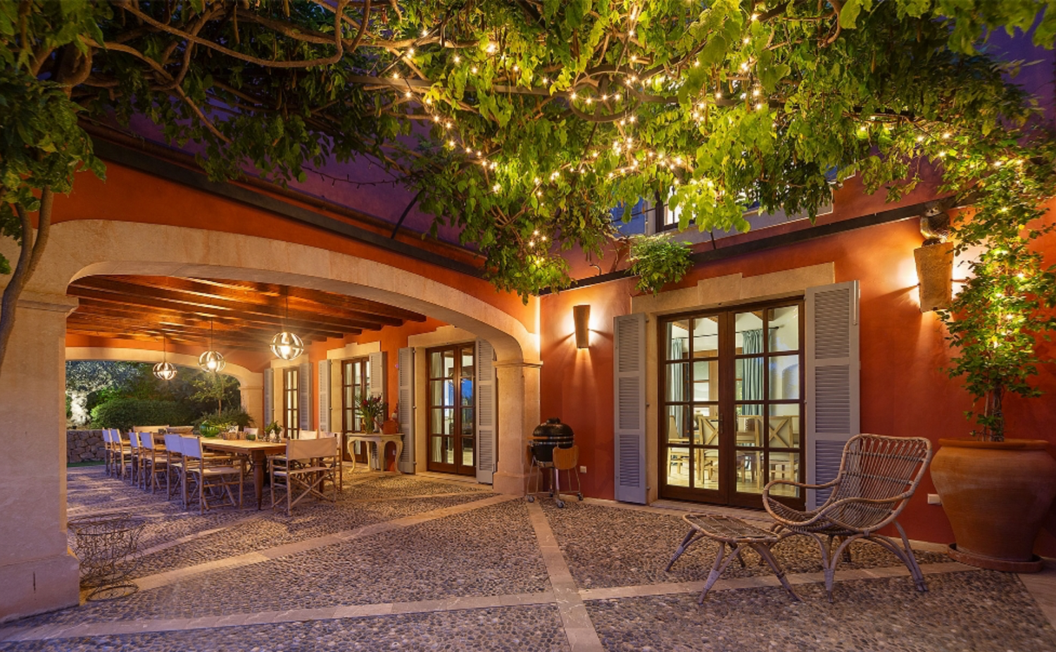 Beautiful outdoor patio with climbing vines and terracotta walls illuminated at dusk.