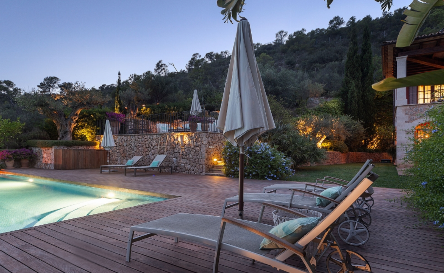 Luxurious poolside deck with lounge chairs and mountain views at sunset.