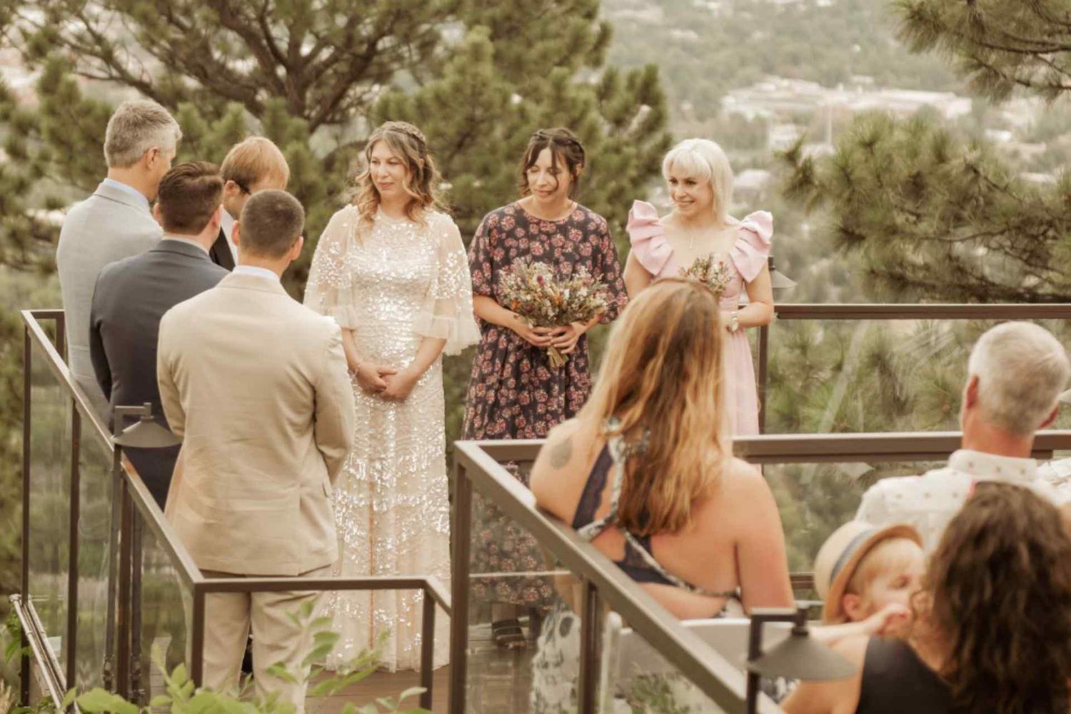 Outdoor wedding ceremony with guests seated on a mountainside deck.