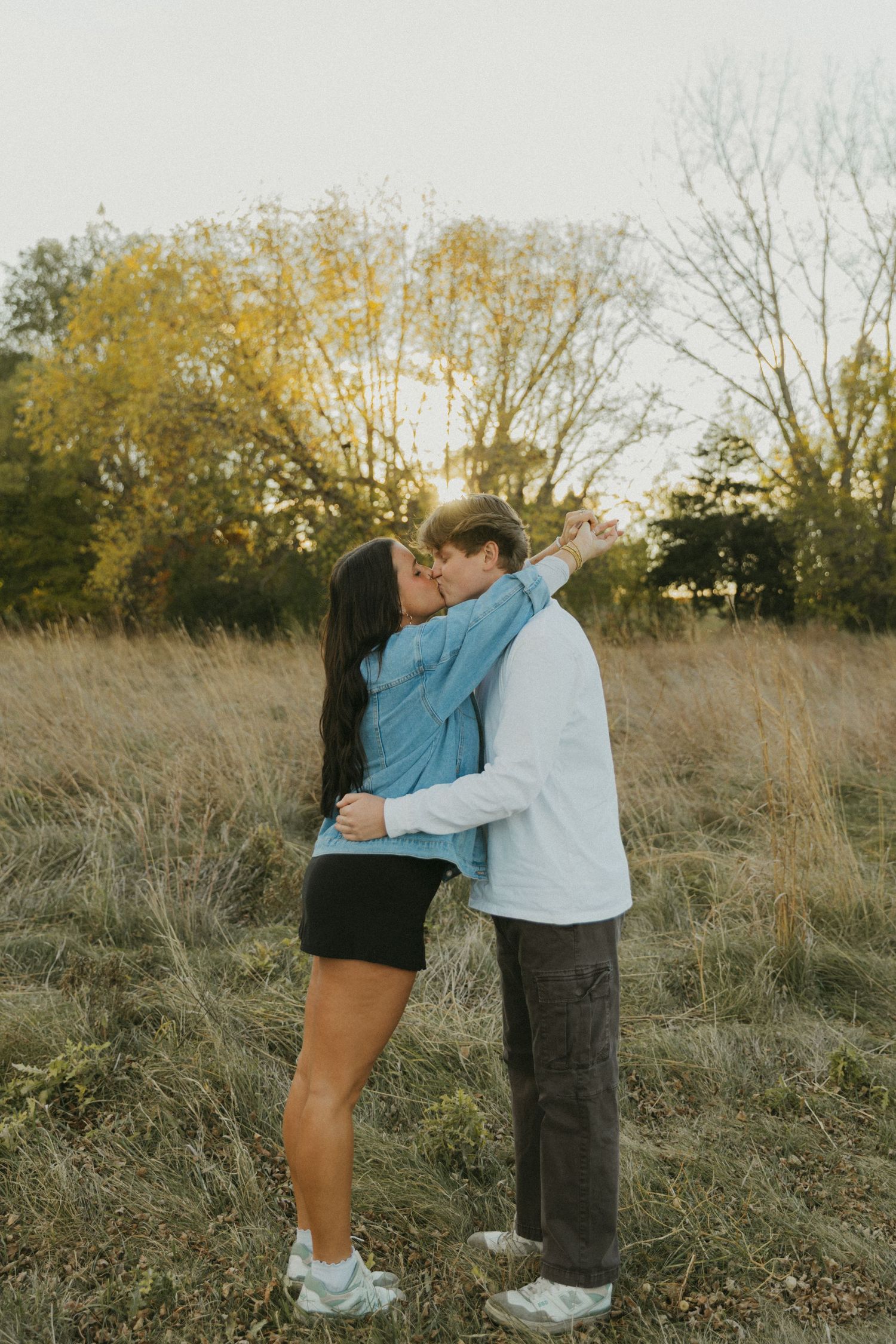 Children sharing an affectionate moment in a field of tall autumn grass.