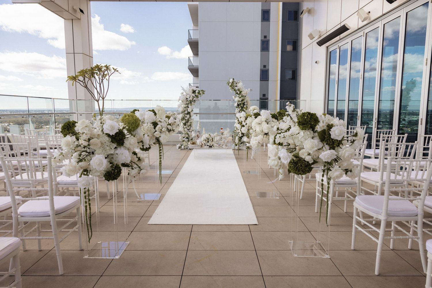 Elegant white wedding reception hall with crystal chandeliers and covered chairs.