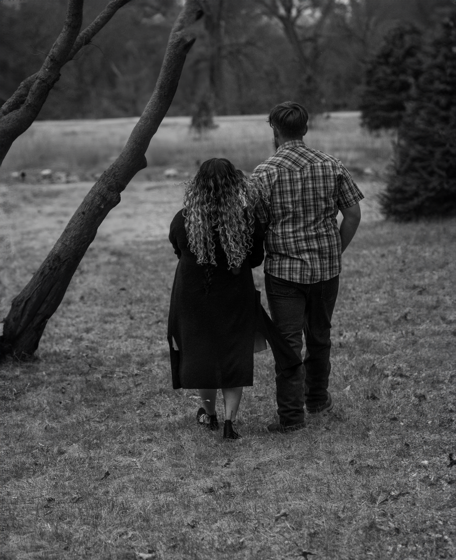 A couple stands together looking out over a scenic landscape in black and white.