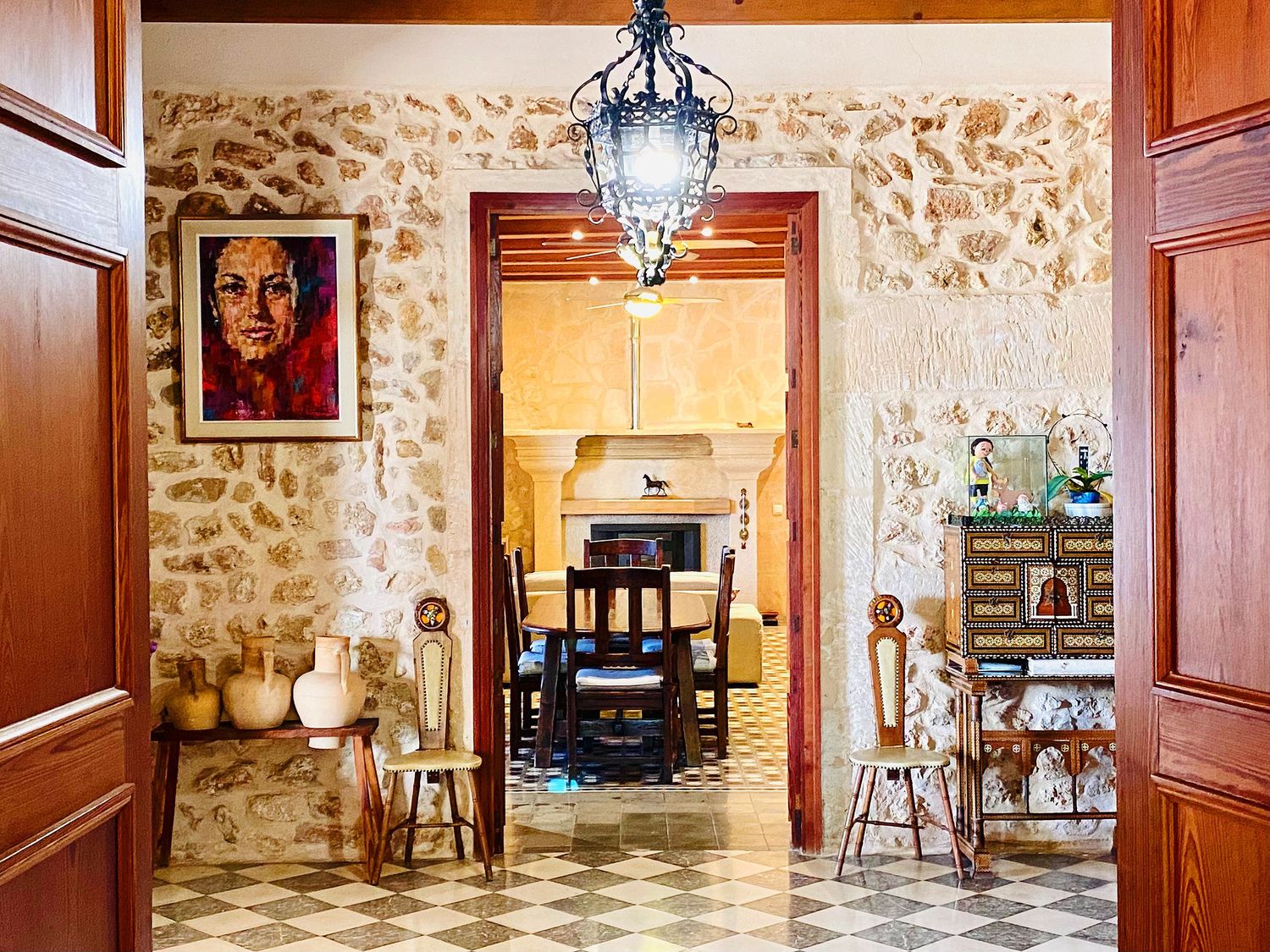 Stone-walled entrance hallway with tiled floors, hanging lantern, and decorative artwork.