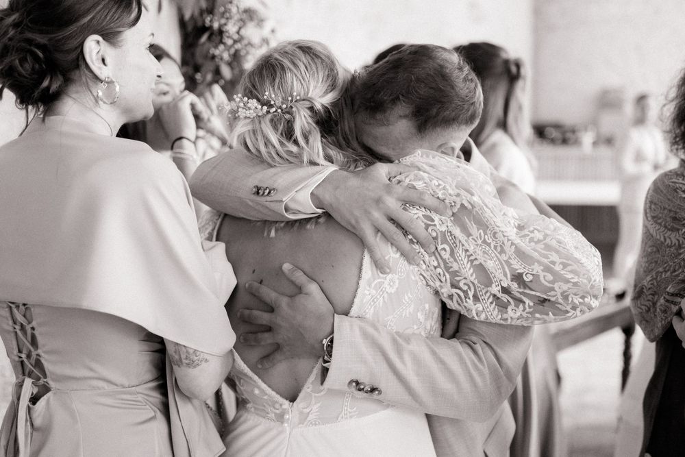 Emotional black and white photo of a bride and groom sharing a heartfelt hug at wedding.