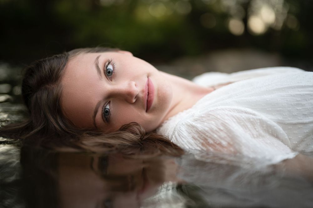 shelby county high school senior portrait. girl lying in creek water at  shoal creek park.  ethereal feel