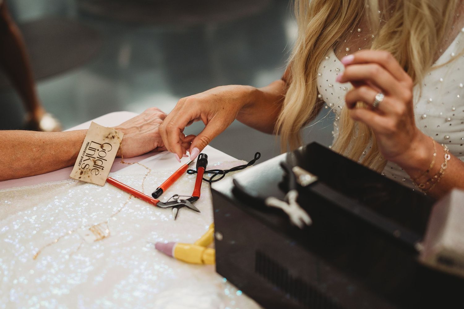 Multiple hands working together on a craft project at a well-lit table.