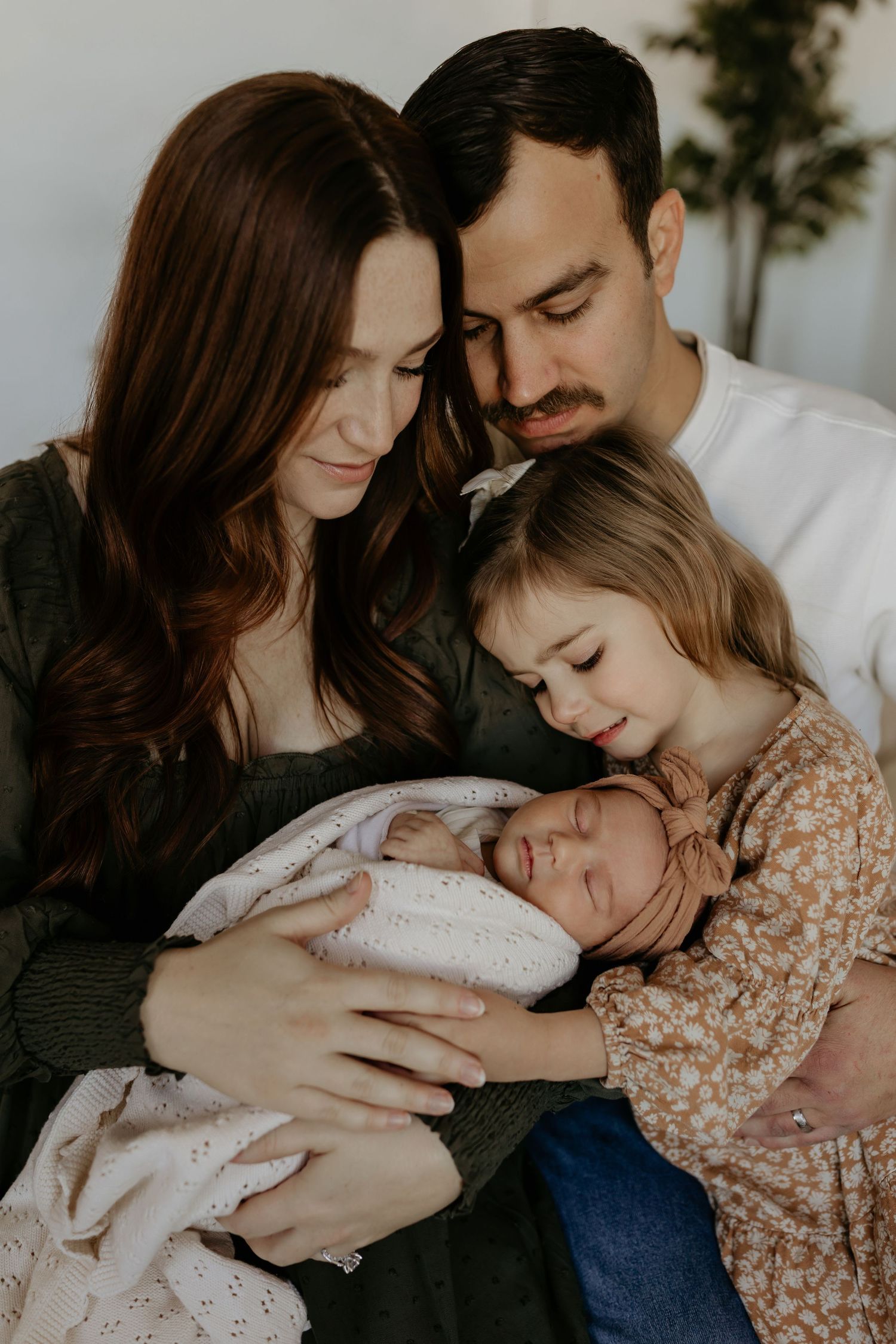A tender intimate moment as mother in peach-colored top cradles sleeping newborn wrapped in brown blanket.