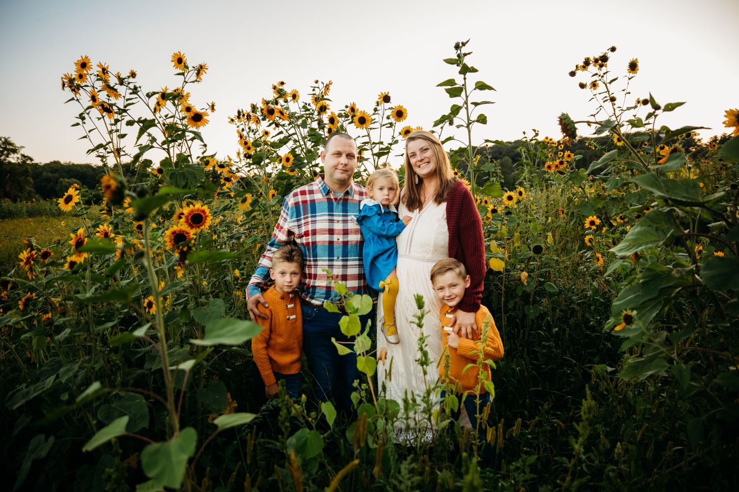 Family portrait in a vibrant sunflower field during summer.