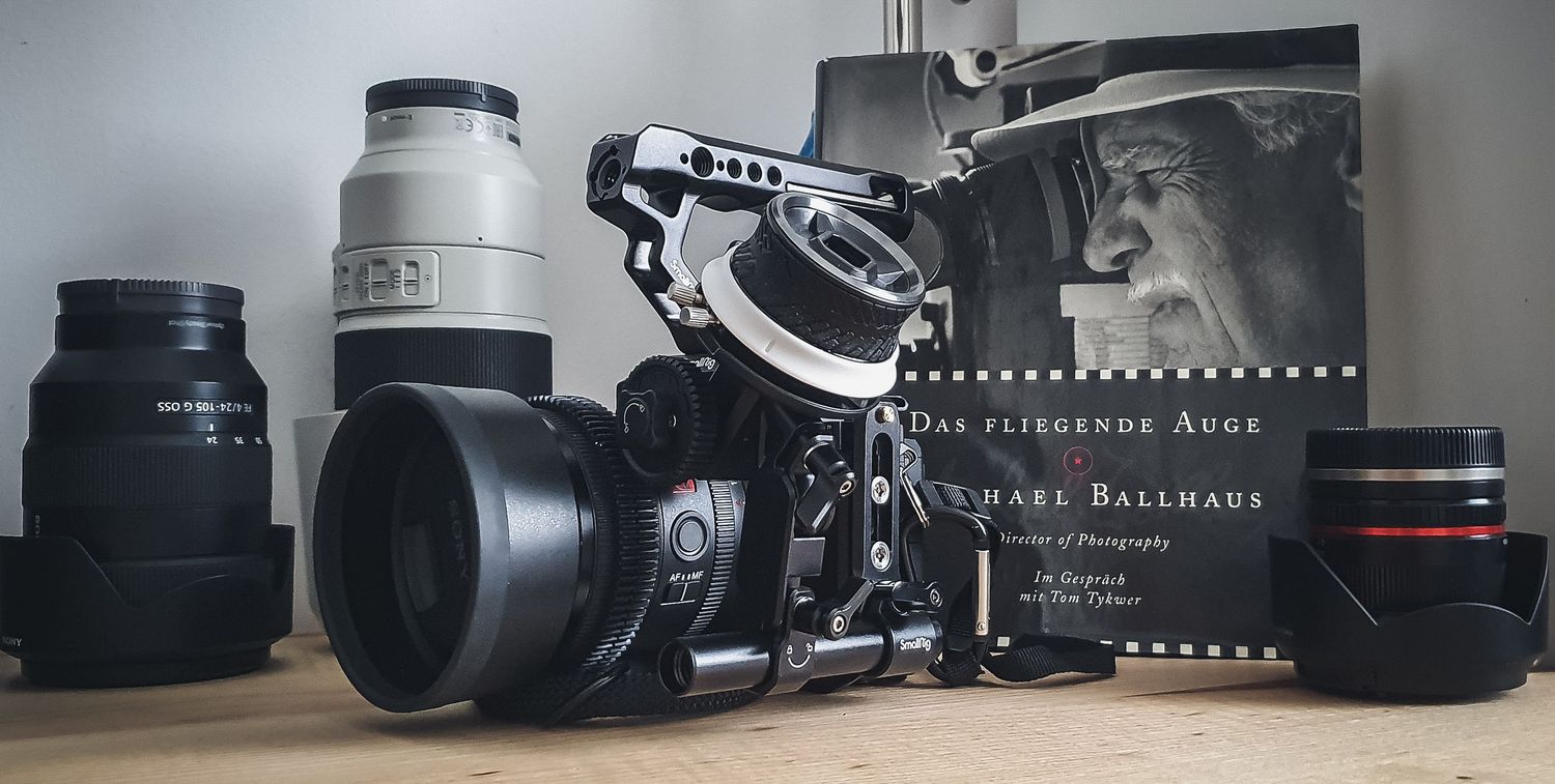Collection of vintage and modern camera equipment including lenses and film rolls arranged in a row on a surface.