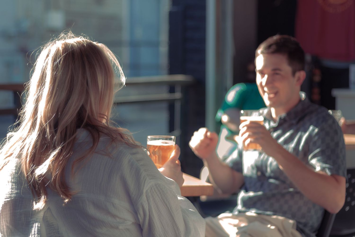 A couple smiles and laughs together at an outdoor restaurant.