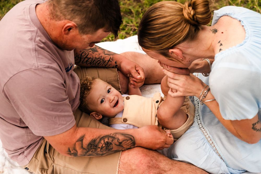 Happy family moment with parents playfully interacting with their child on a sunny day.
