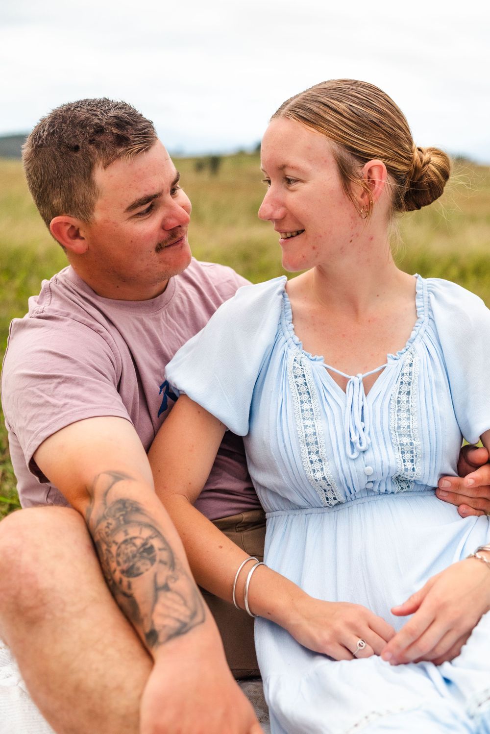 Loving couple embracing in casual outdoor portraits against a natural landscape.