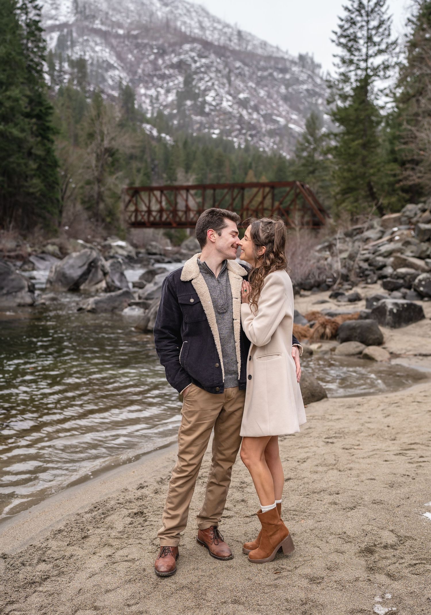 Romantic moment by mountain stream with rustic bridge in background.