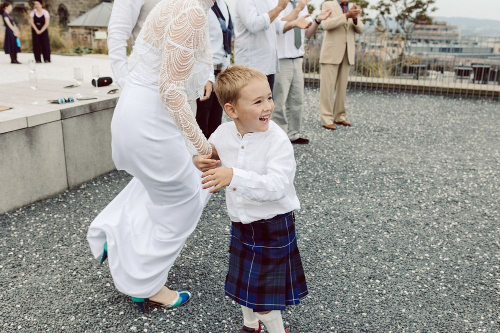 Wedding guests in formal attire share celebratory moments on stone terrace.